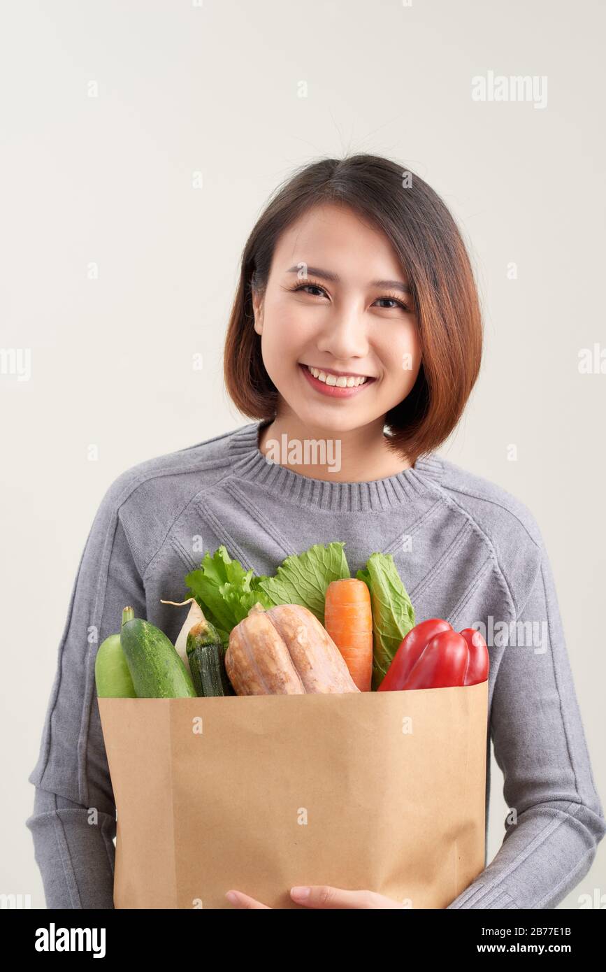 Horizontal orientation color image of a woman holding a paper bag overflowing with vegetables / Adding Veggies to your Diet Stock Photo