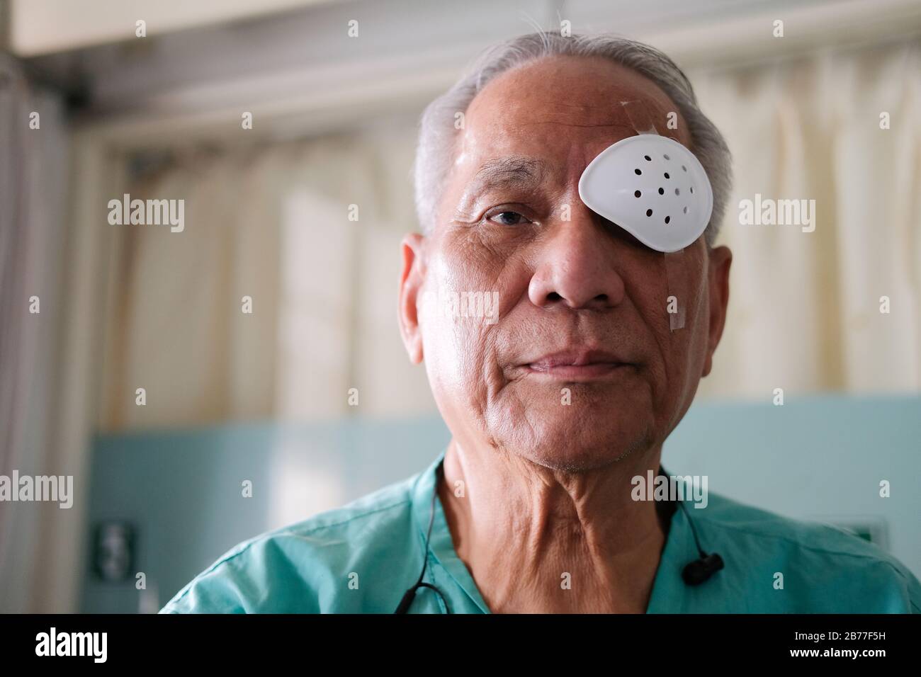 patient covering eye with protective shield & medical plaster after