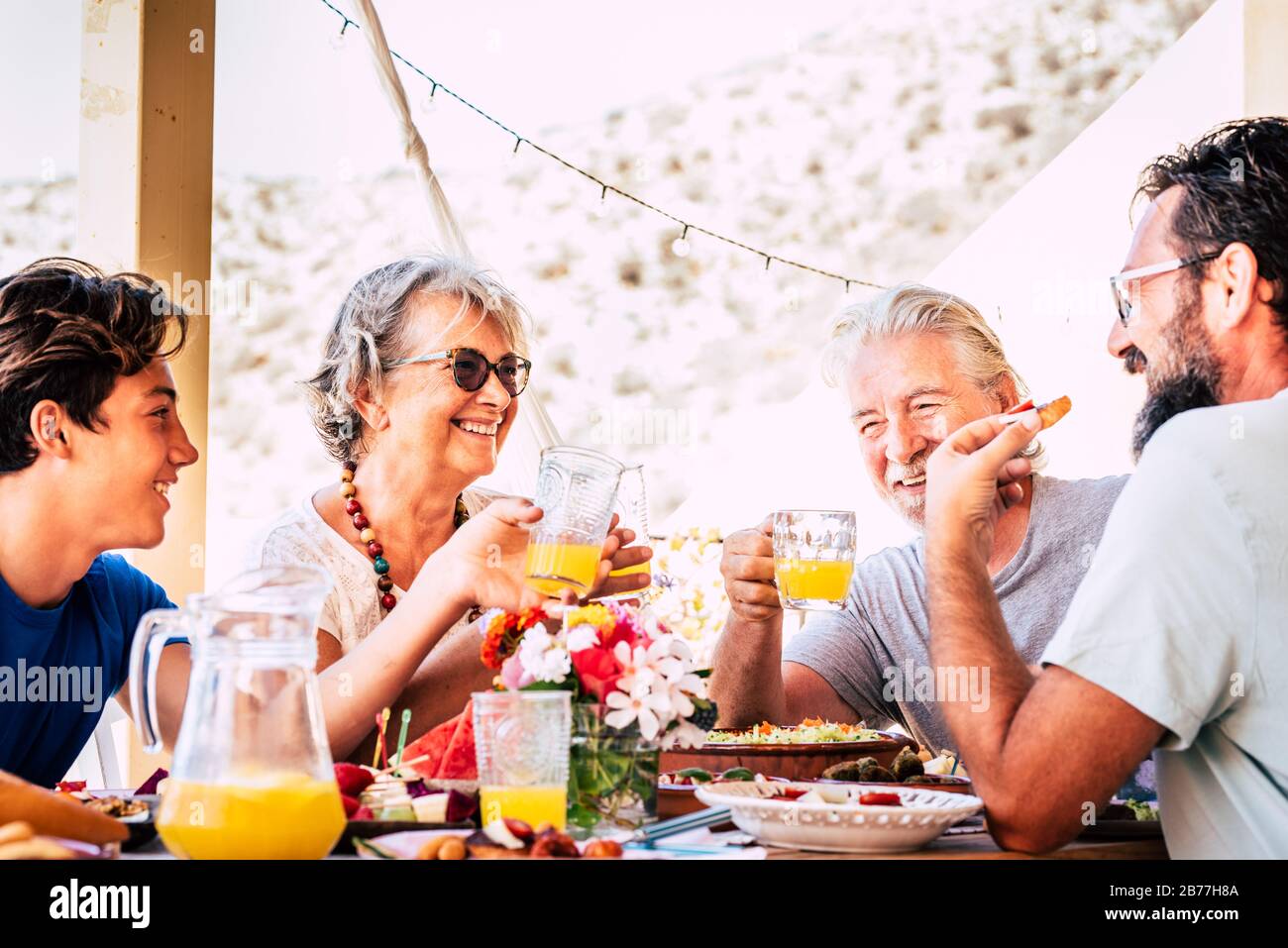 Happy and cheerful mixed ages and generations caucasian family stay together eating at lunch at home or restaurant - people enjoy fathers and son cele Stock Photo