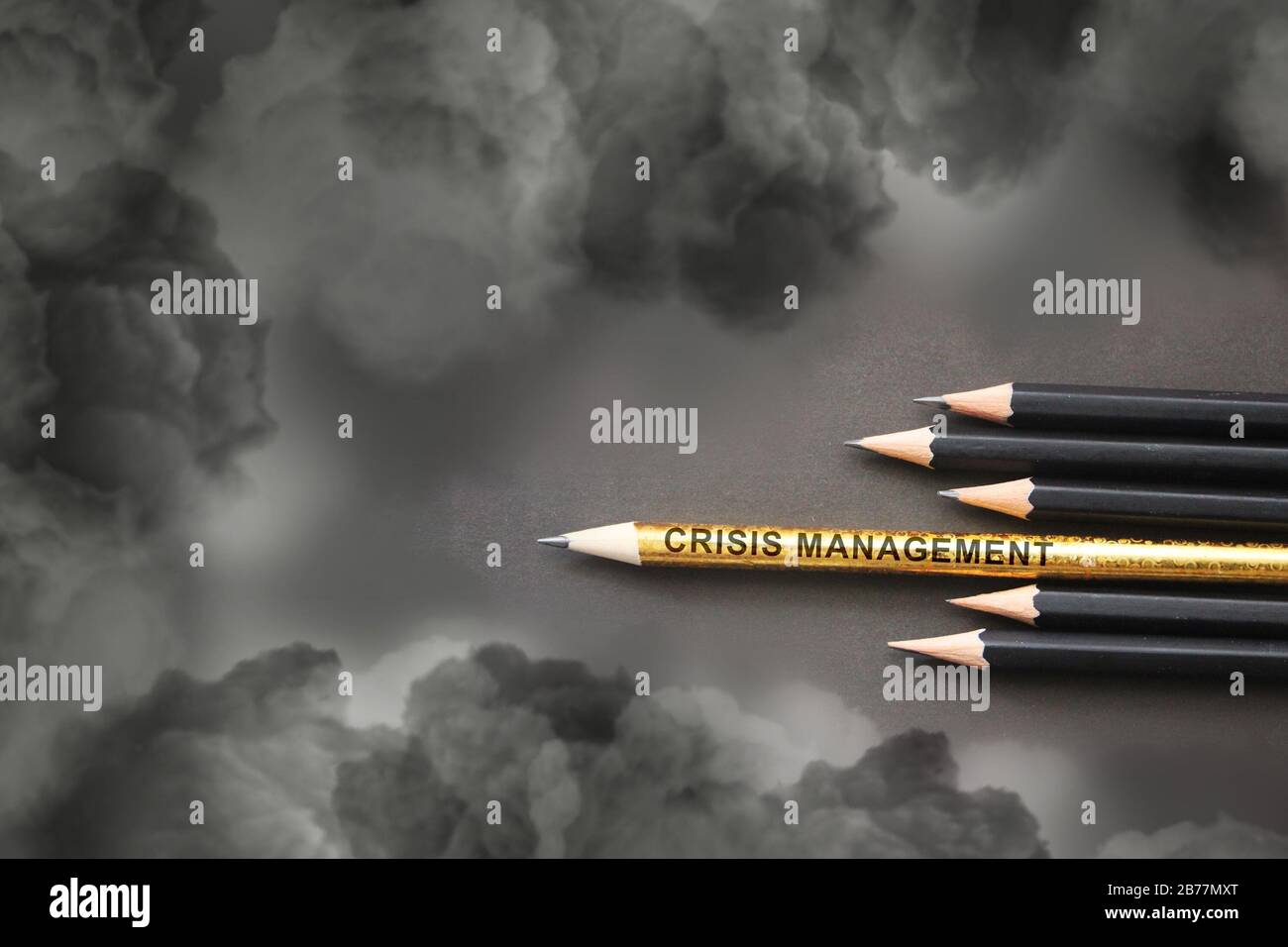 Crisis Management written on pencil composition reminding weapons against heavy clouds. Crisis management or risk assets concept Stock Photo