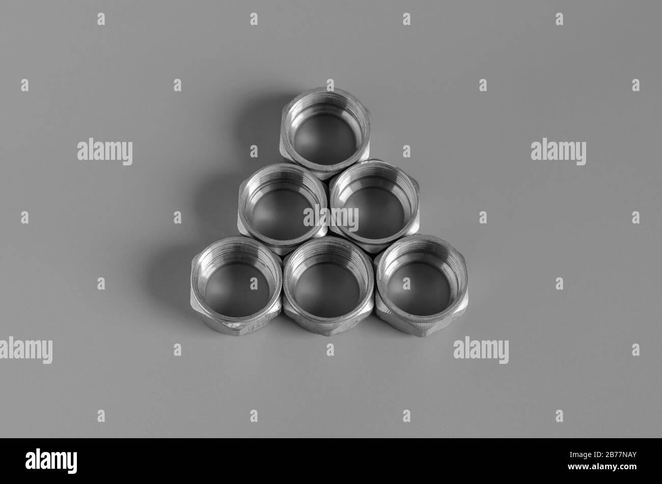 Brass nuts for pipe compression fittings. A triangle of six nuts on a gray background. Close-up. Selective focus. Stock Photo