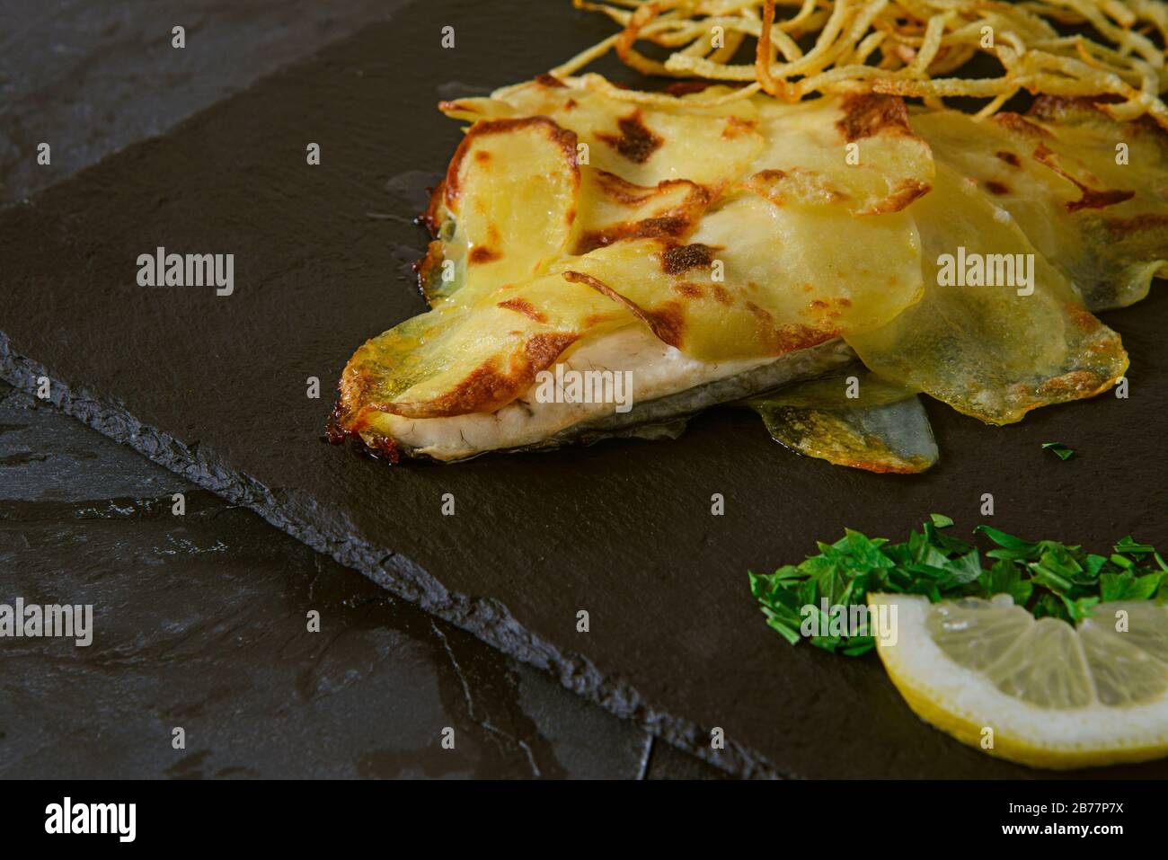 Sea bream in potato crust with fried chopped onion - Horizontal studio shot Stock Photo
