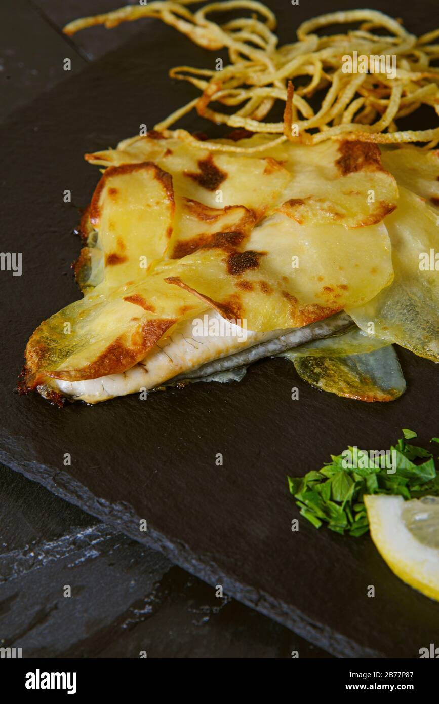 Sea bream in potato crust with fried chopped onion - Vertical studio shot Stock Photo