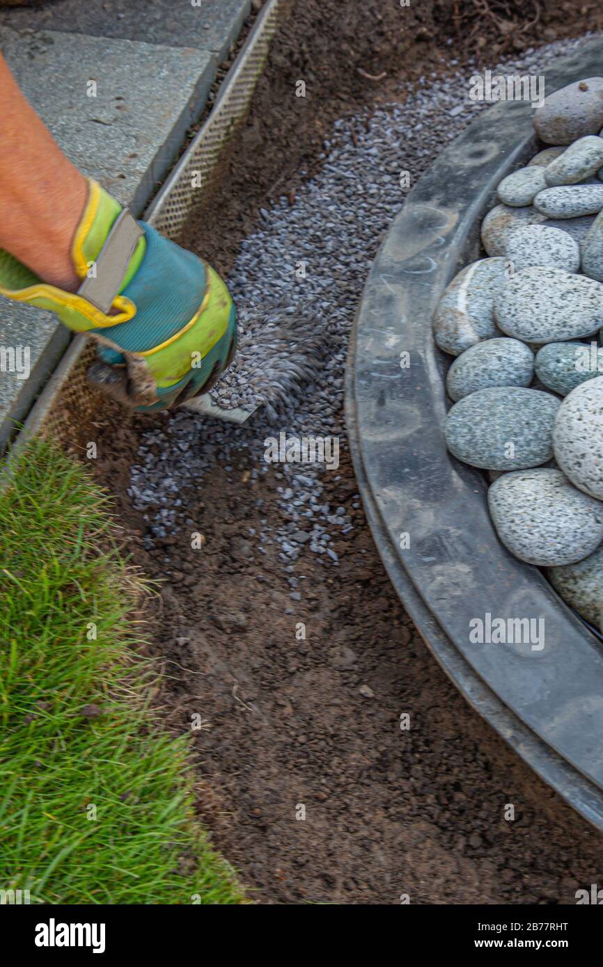 a hand with work glove filling gritting material into the curb of a garden fountain Stock Photo