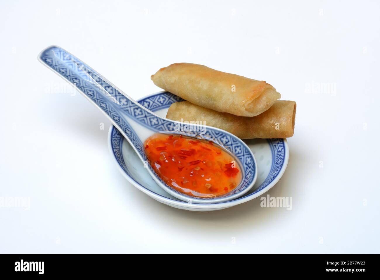 Chilli sauce in Asian spoon and mini spring rolls, Germany Stock Photo
