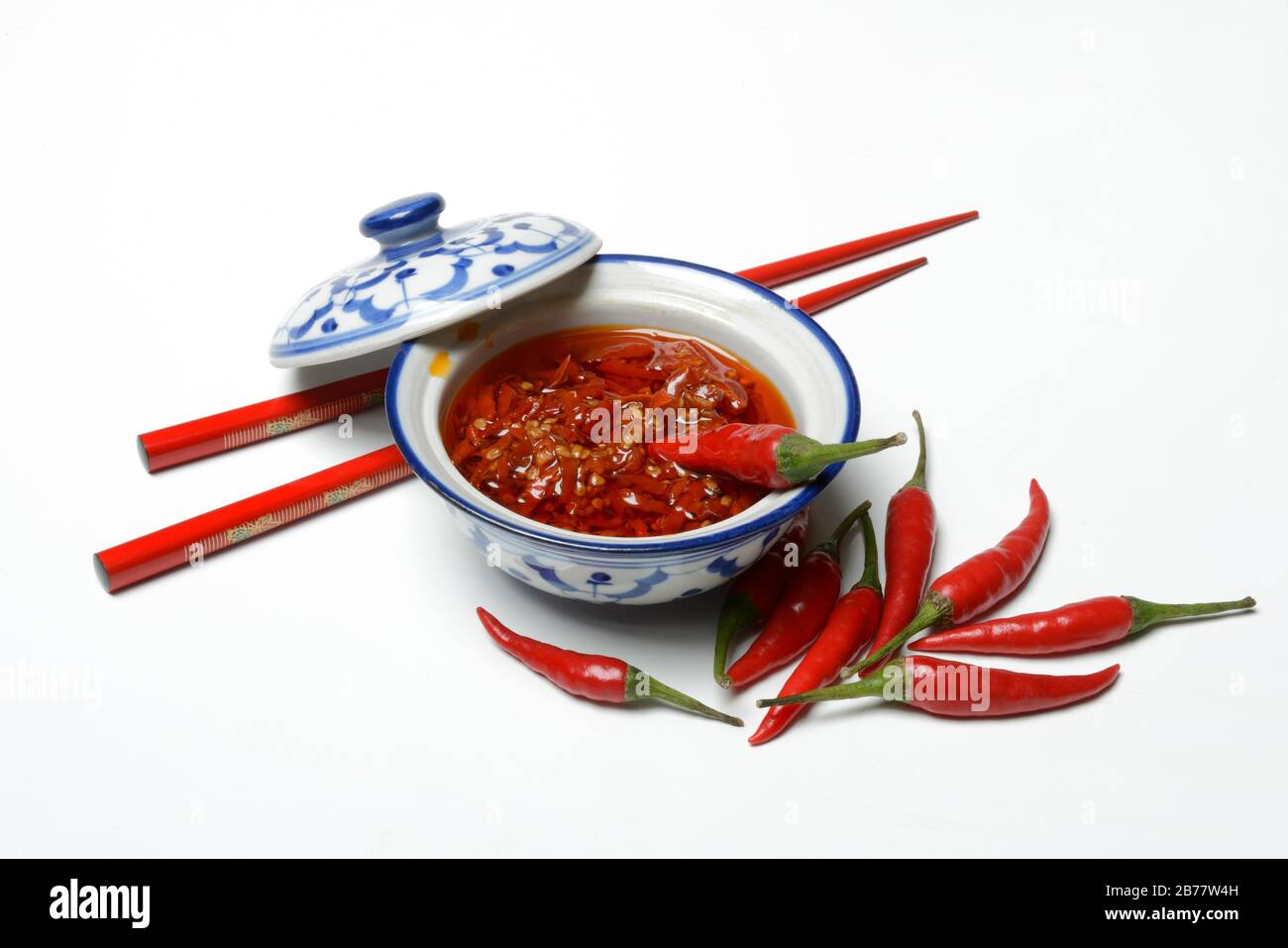 Crushed chilli peppers in oil in shell and red chopsticks, Germany Stock Photo