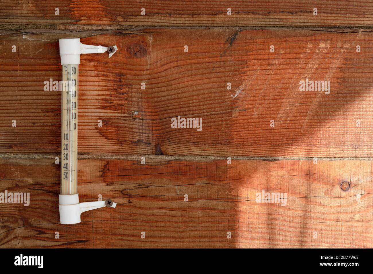 A wooden wall of pine horizontal boards, a rough surface, an old mercury thermometer, warm sunlight. For the background of the weather. Stock Photo