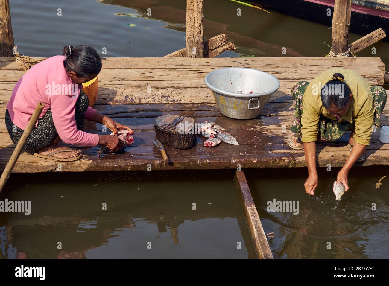 Frauen sitzen auf Bootssteg und nehmen Fische aus, Dorf Naung Boh, südlicher Inle See, Shan-Staat, Myanmar Stock Photo
