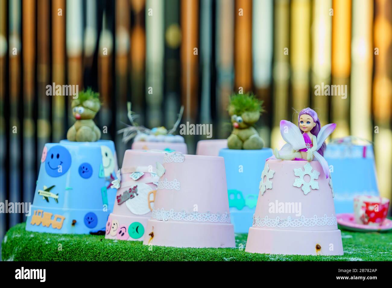 Small smiling fairy with wings and green trolls sitting on flower pots. Selective focus and blurred background Stock Photo