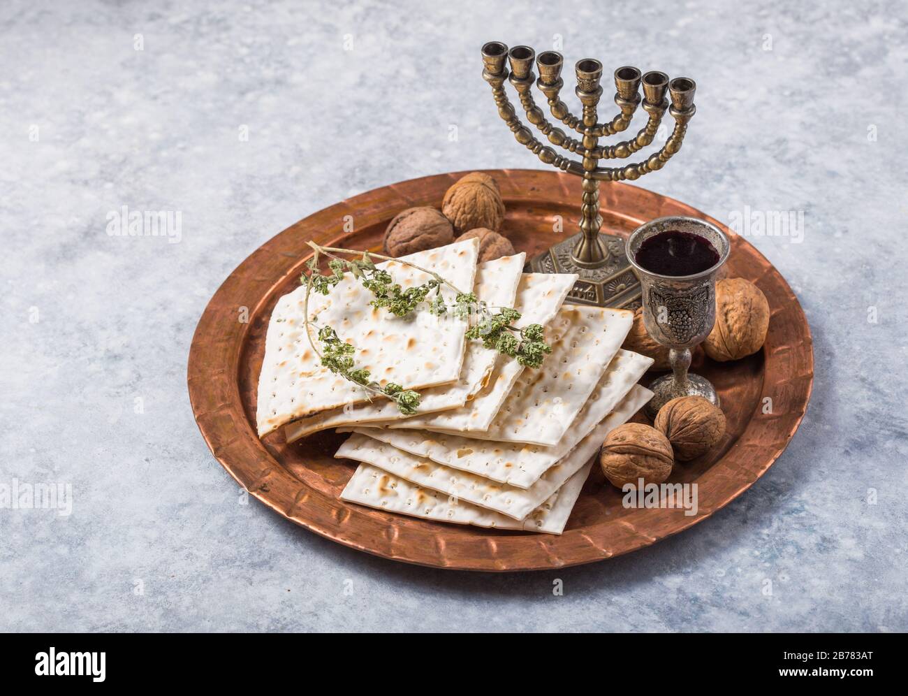 Passover, the Feast of Unleavened Bread, matzah bread and red wine glasses on the shinny round metal tray. Stock Photo