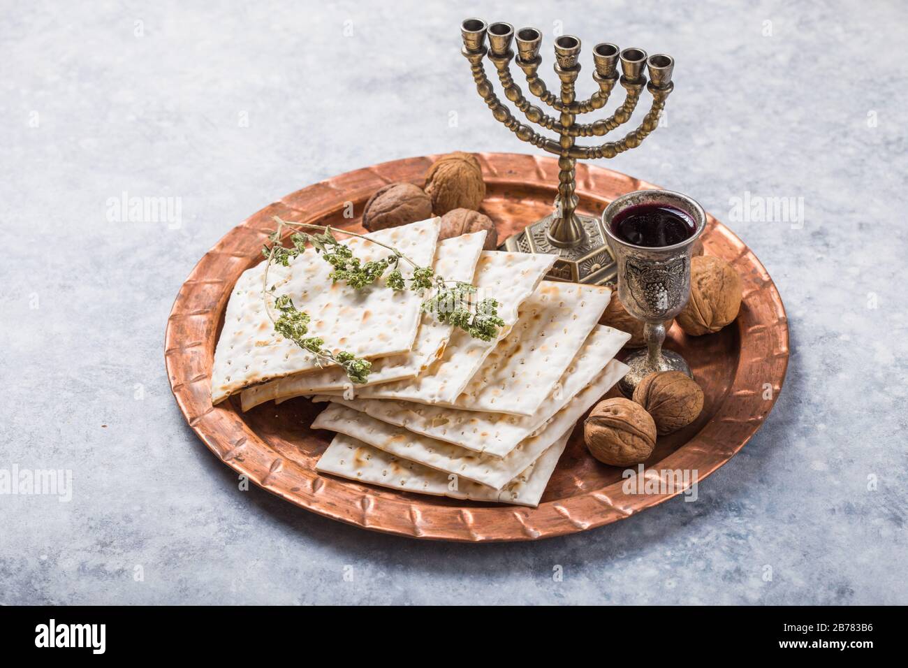 Passover, the Feast of Unleavened Bread, matzah bread and red wine glasses on the shinny round metal tray. Stock Photo