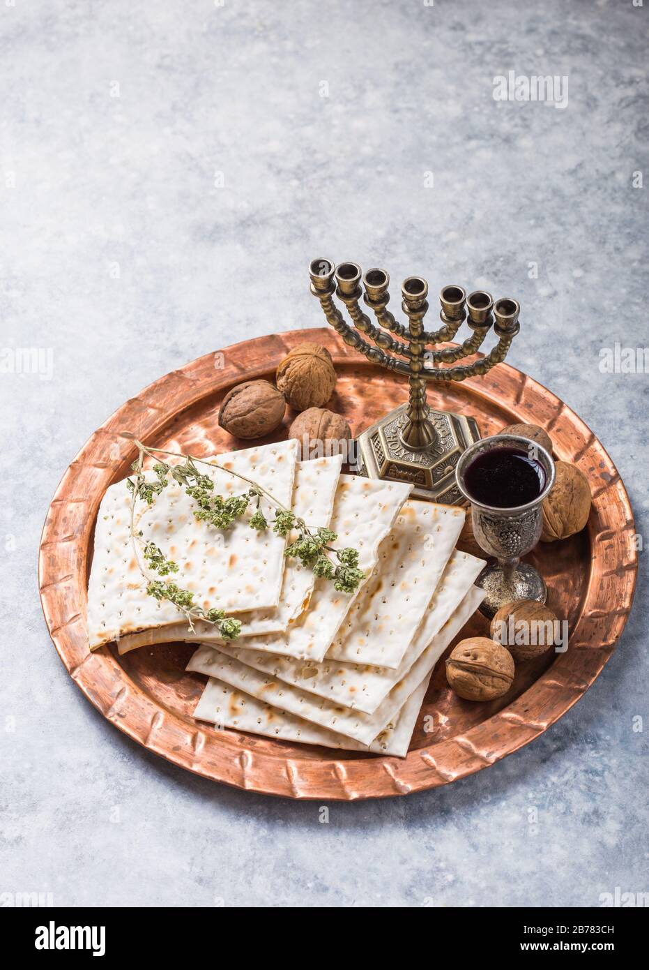 Passover, the Feast of Unleavened Bread, matzah bread and red wine glasses on the shinny round metal tray. Stock Photo