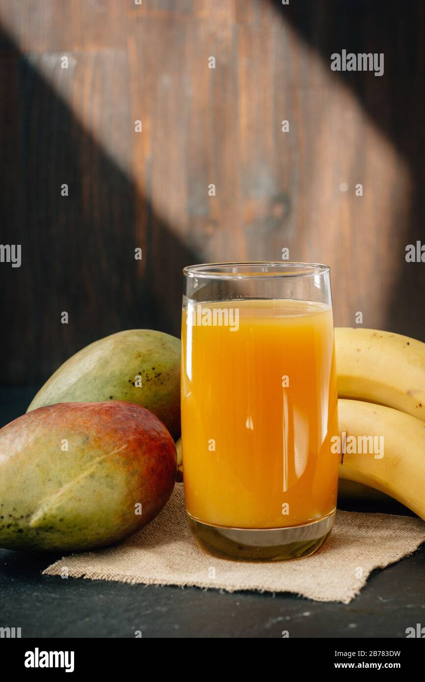Glass filled by mango and banana juice over black surface Stock Photo