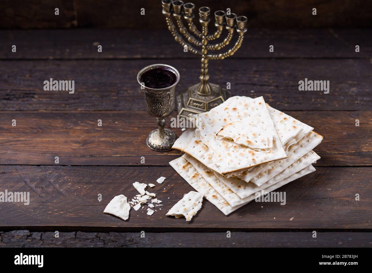 Red kosher wine with a white  matzah or matza on a vintage wood background presented as a Passover seder meal with copy space. Stock Photo