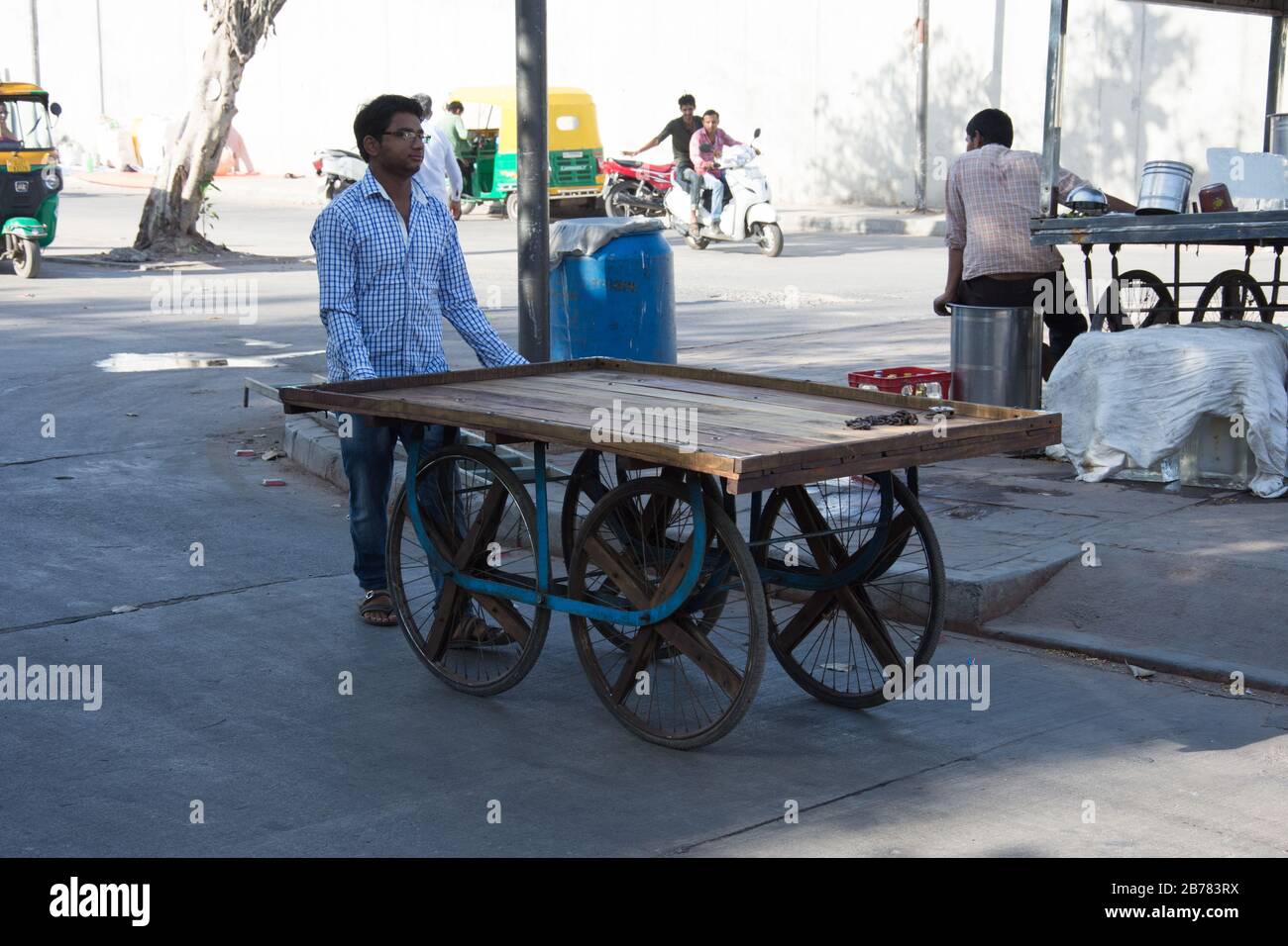 Ahmedabad / India / April 11, 2017 Indian man caring wheeled table of