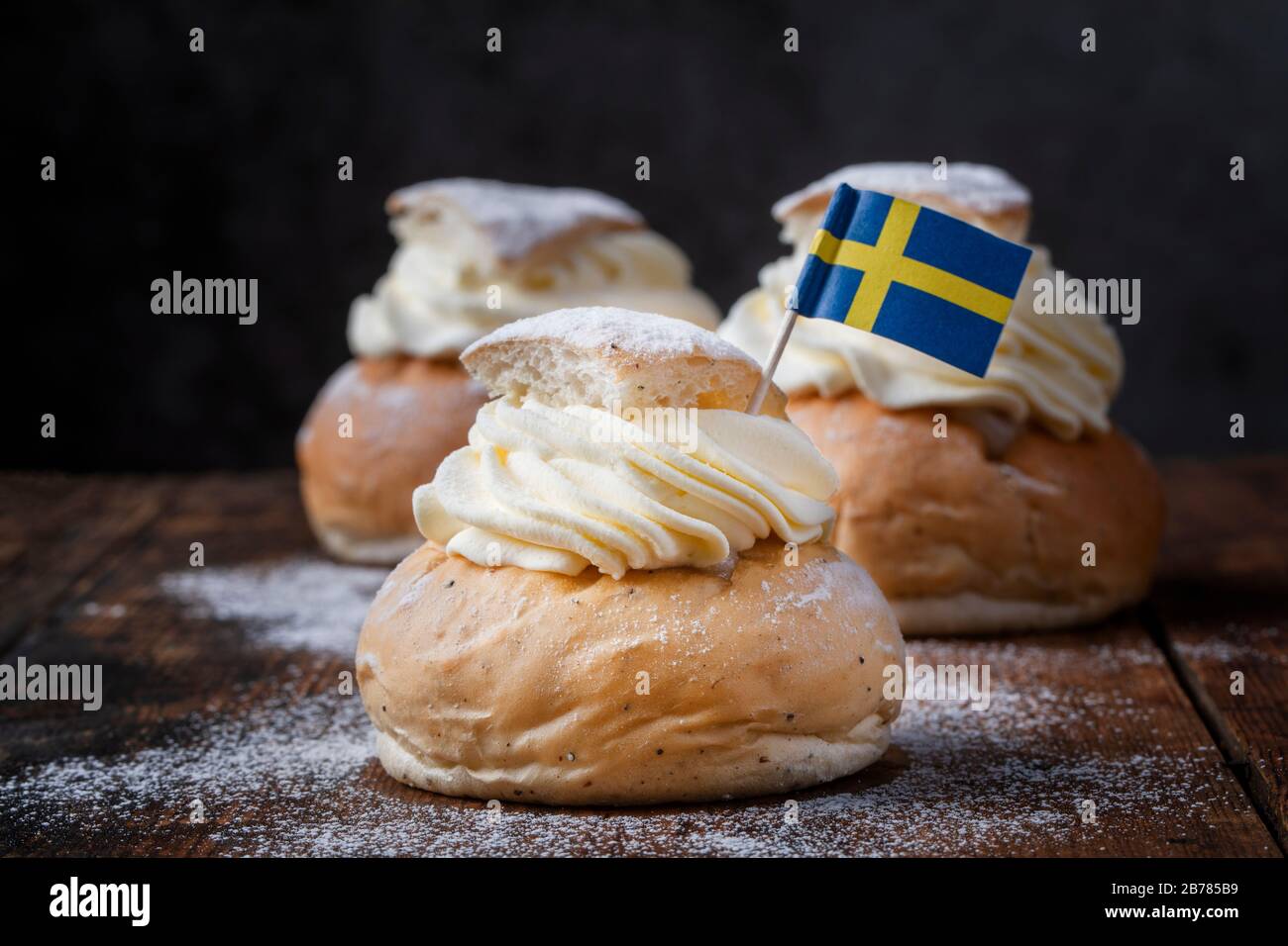 Semlor, fastelavnsbolle, fastlagsbulle on dark background.  Traditional scandinavian cream filled cardamom buns with almond paste.  Decorated with a S Stock Photo