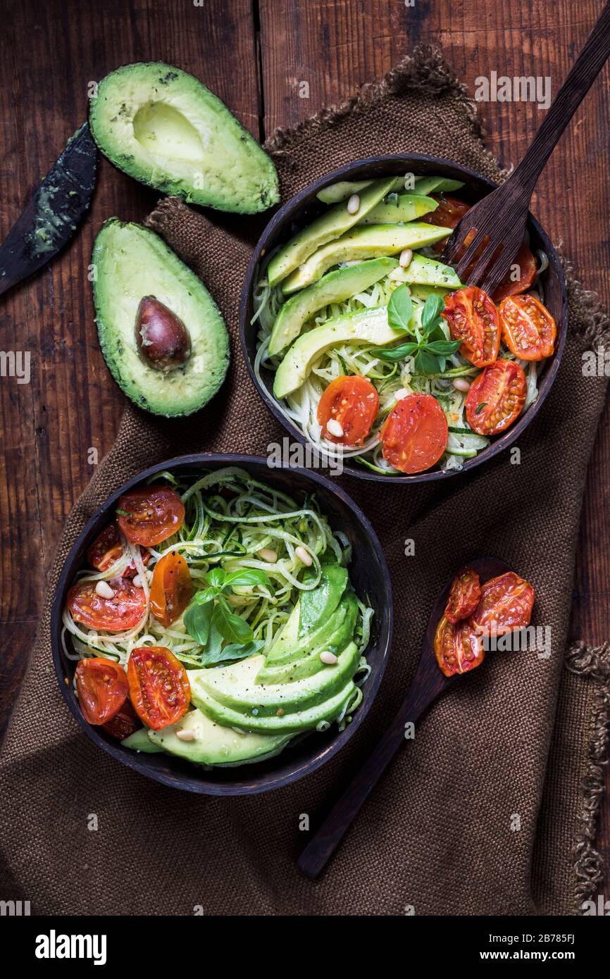 Healthy salad with zoodles zucchini noodles, oven roasted tomatoes and avocado. The salad is seen from above, and it is served in recycled environment Stock Photo