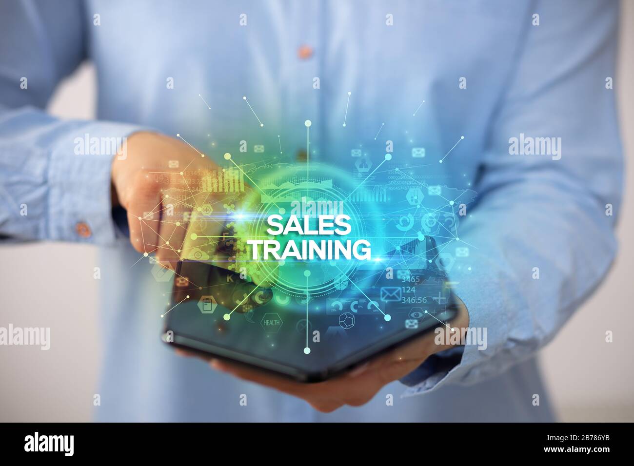 Businessman holding a foldable smartphone with SALES TRAINING inscription, new business concept Stock Photo