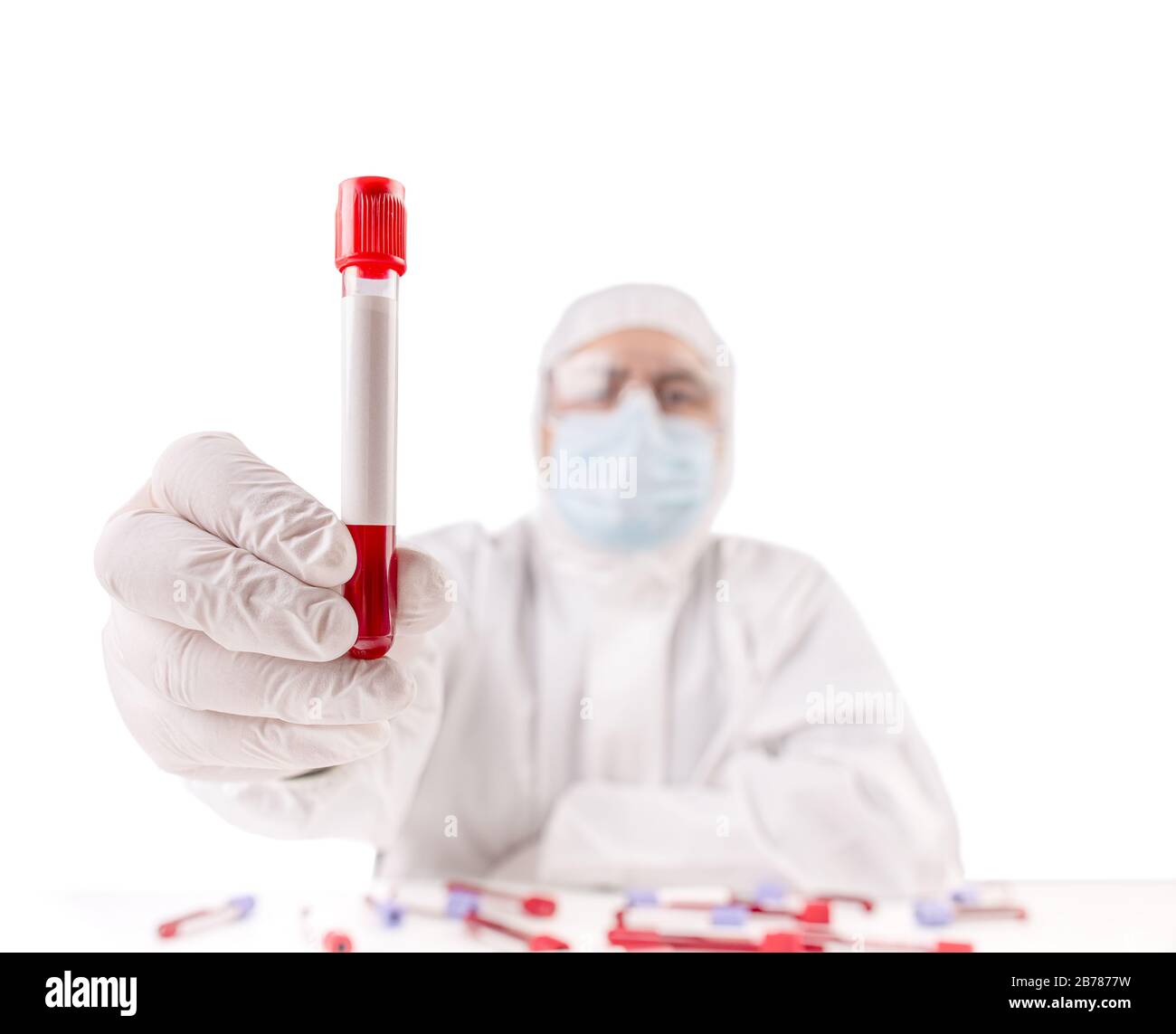 Male doctor's hands in white protective clothing and medical gloves holding blood test tube Stock Photo