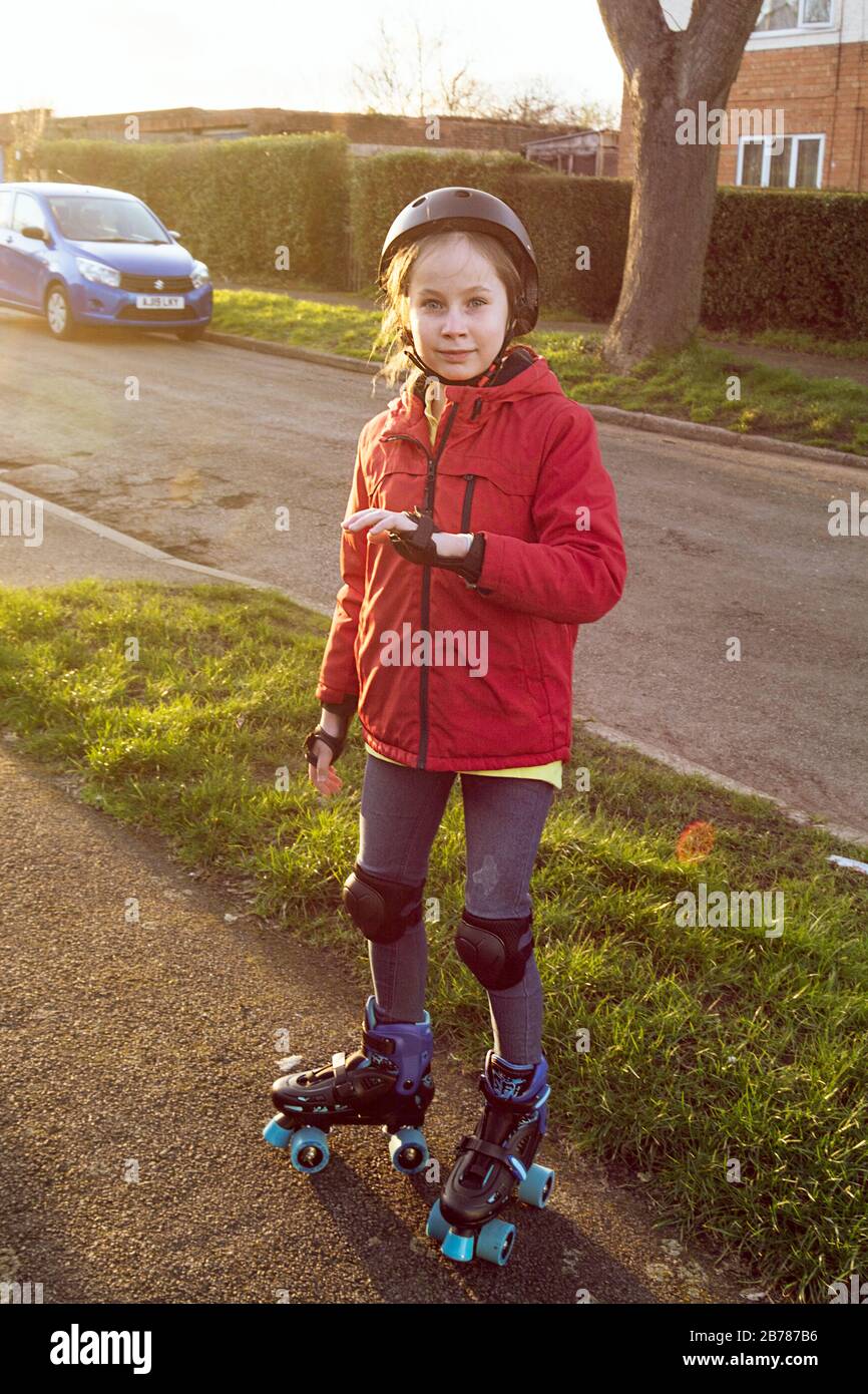 Ten years old girl in a helmet, elbow pads and knee pads rollerskating
