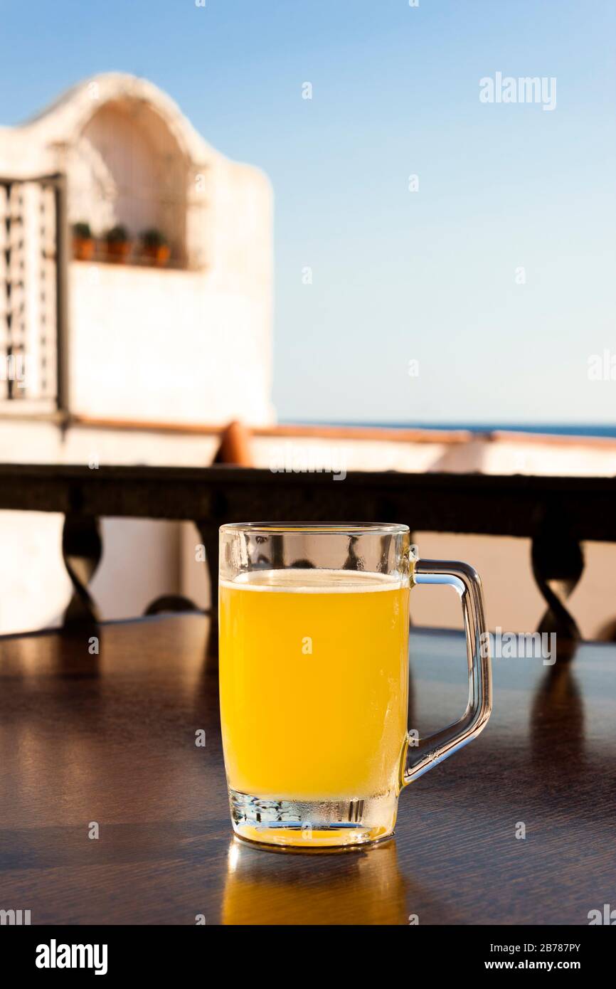 Glass of cold beer with lemon on the table of a terrace in a bar next