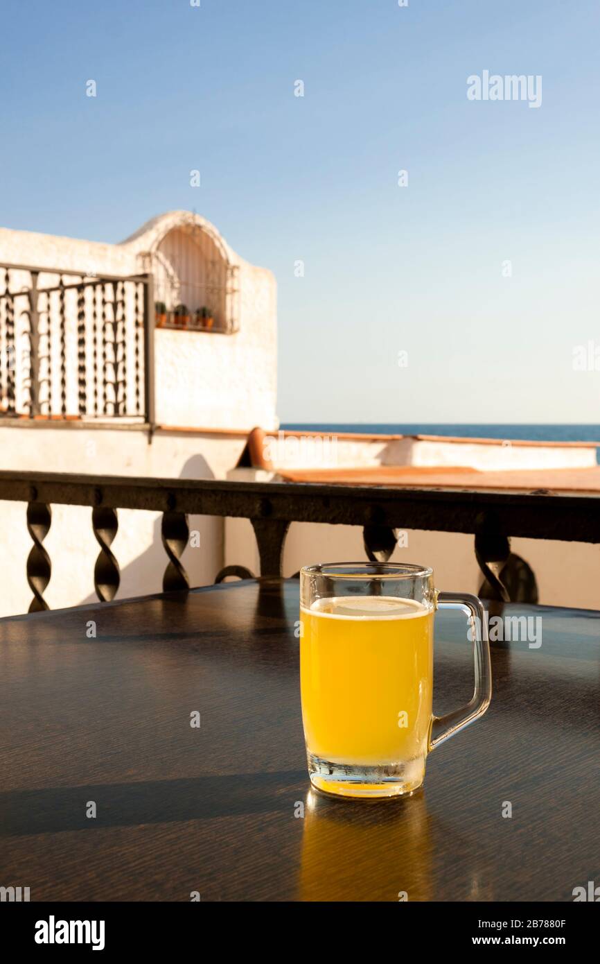 Glass of cold beer with lemon on the table of a terrace in a bar next