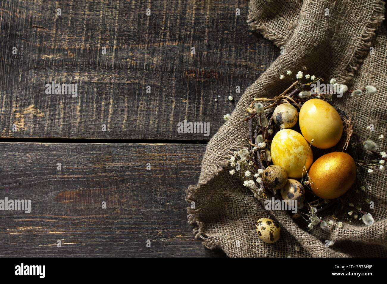 Golden easter eggs in nest and easter decoration on wooden table. Top view flat lay background. Copy space. Stock Photo