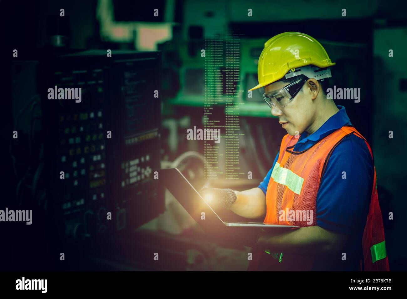worker operate CNC machine with G-Code monitor, high skill labor work industry with safety clothes dark green color tone for high technology skill con Stock Photo