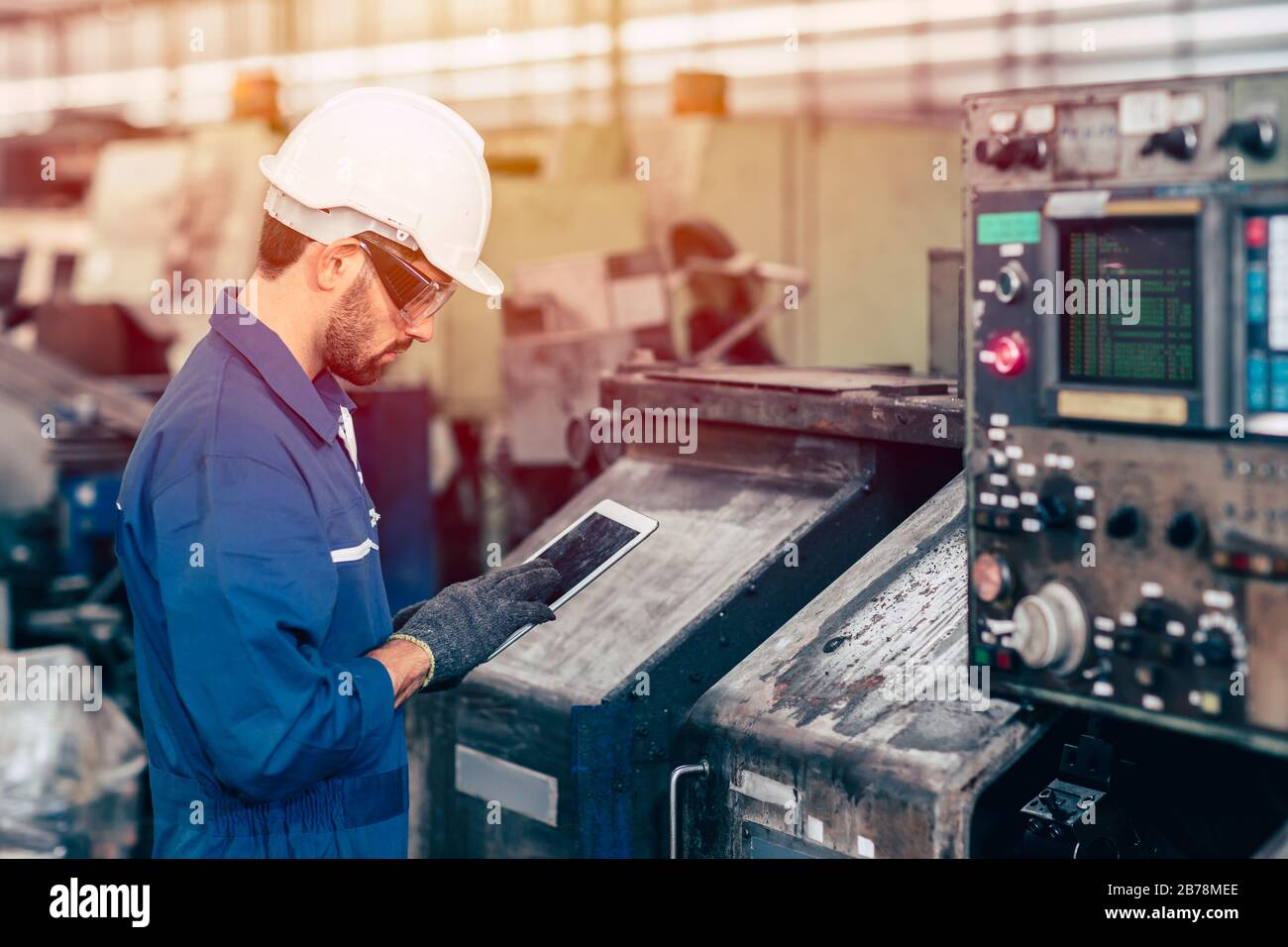 engineer setup the CNC machine with G-Code programming upload from Computer Tablet for technology in heavy industry. Stock Photo