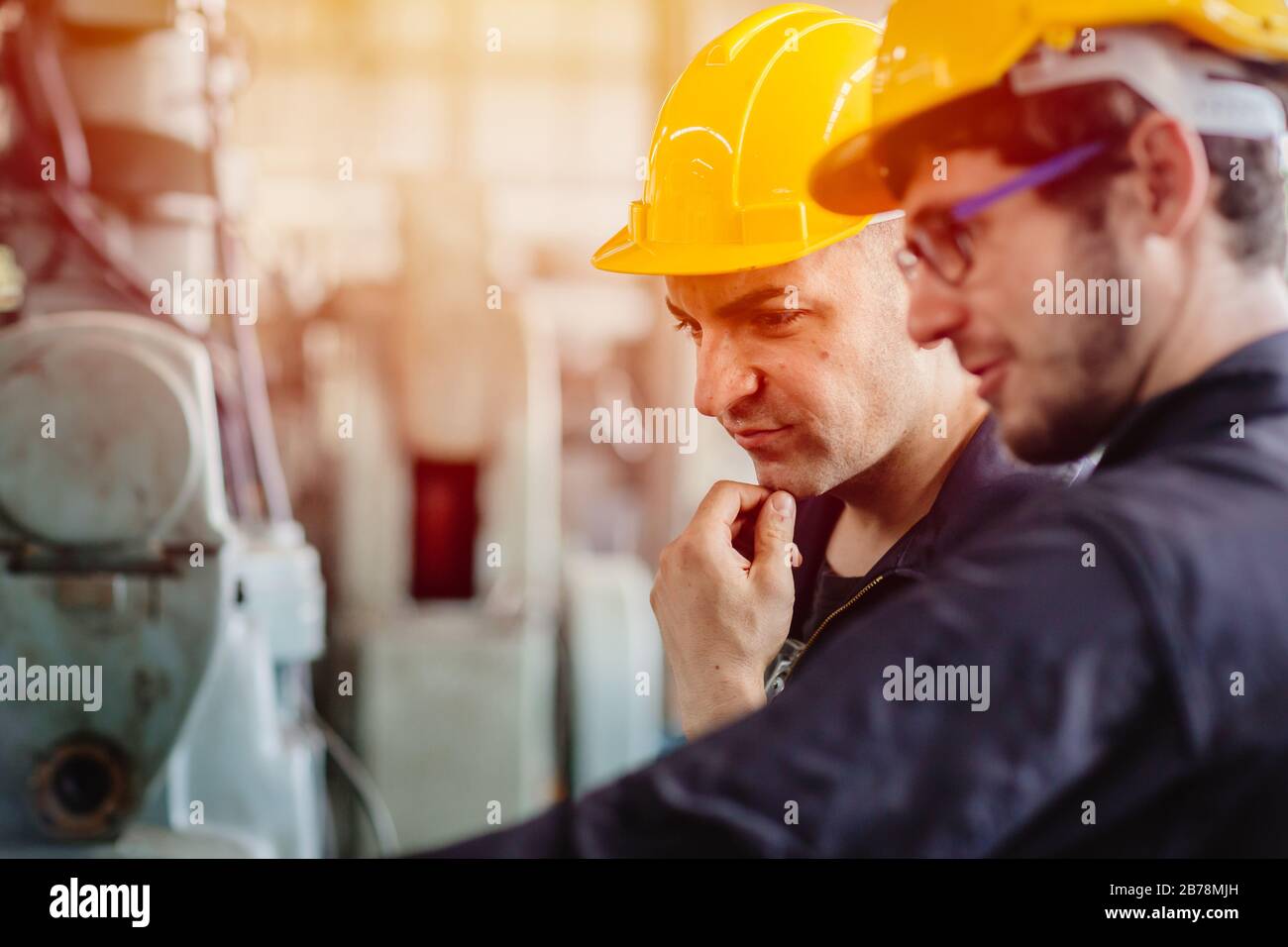 worker thinking, service team working with machine together teamwork in heavy industry factory with safety helmet. Stock Photo