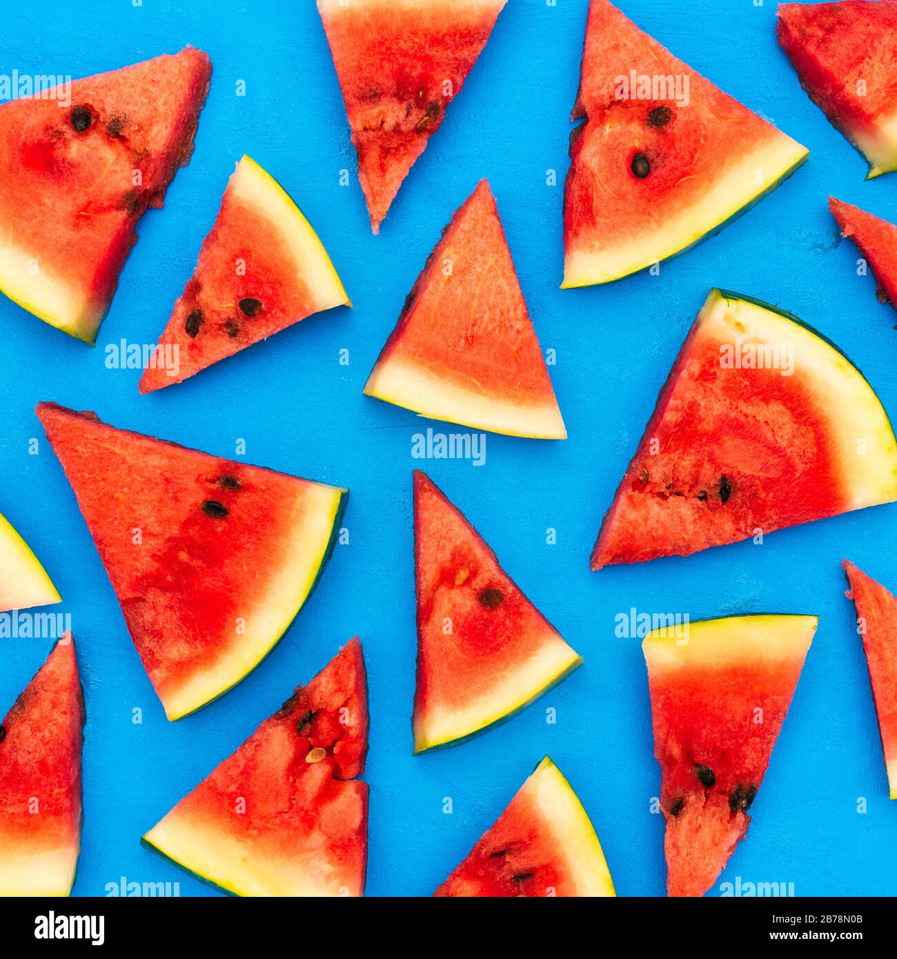 Slices of a watermelon triangular in shape on a blue background. Summer time concept Stock Photo