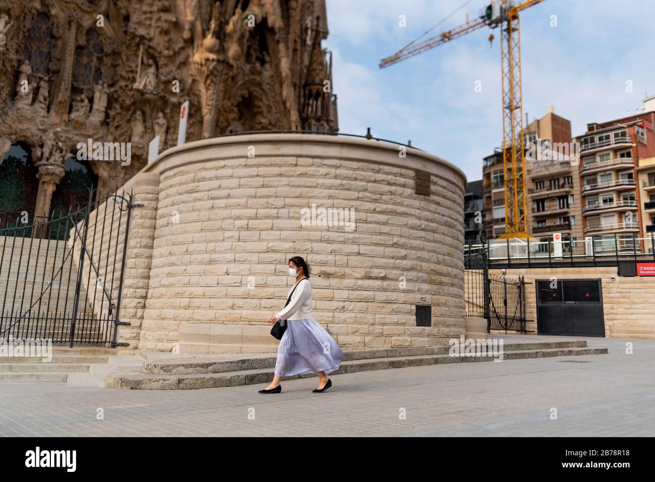 Barcelona, Spain - 14 march 2020: an asian woman walking by the sagrada familia monument wearing protective face mask during the corona virus outbreak Stock Photo