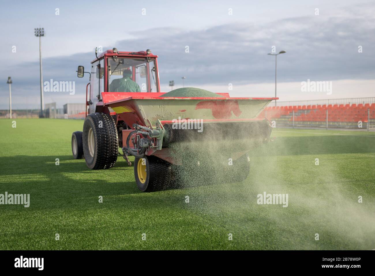 Pouring infill granules in to a football pitch with artificial grass. Stock Photo