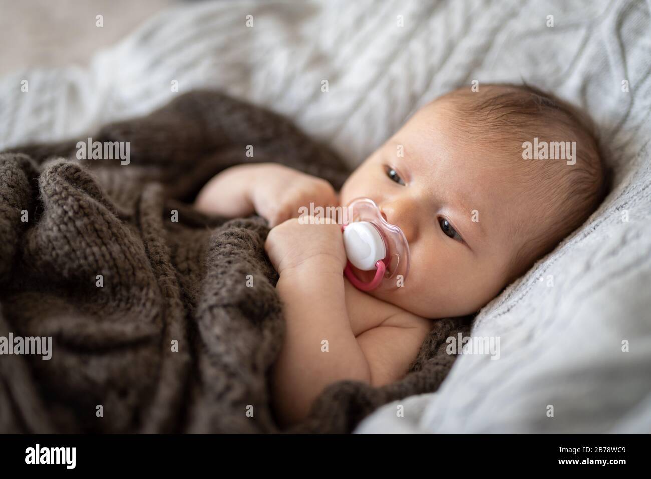 Cute baby girl with pacifier wrapped in blanket Stock Photo Alamy
