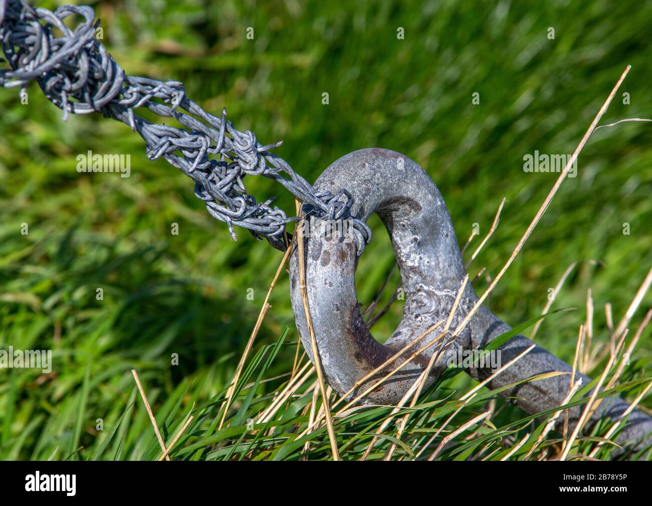 Metal anchor for a barbed wire fence post fixed in the ground Stock Photo