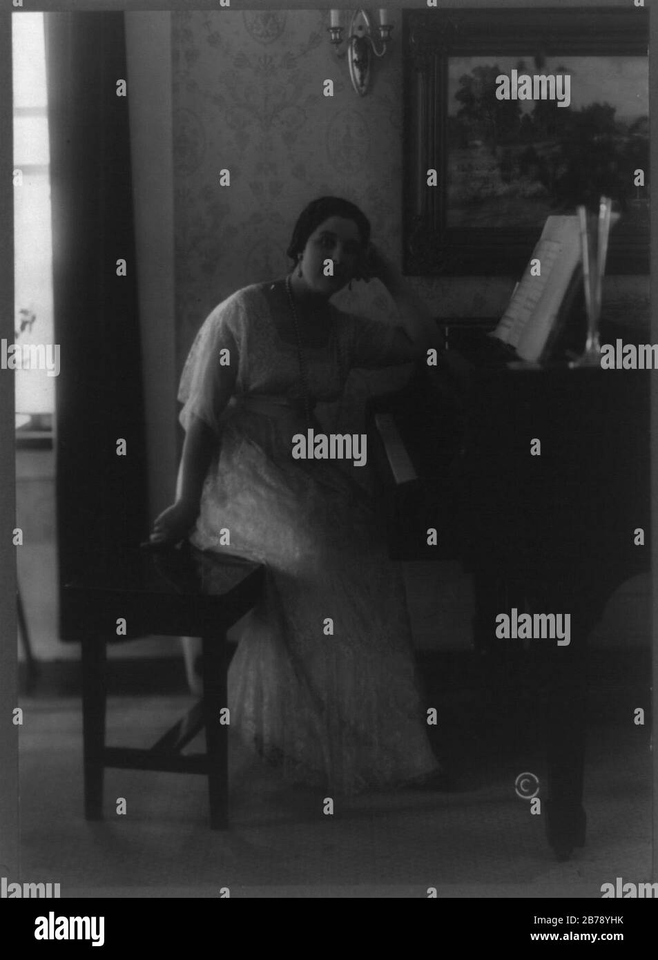 Geraldine Farrar, full-length portrait, seated at piano, facing right, head resting on left hand Stock Photo