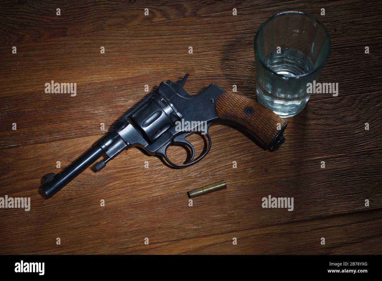 An old metal pistol with a drum on a wooden table.Russian roulette. A  revolver . Stock Photo