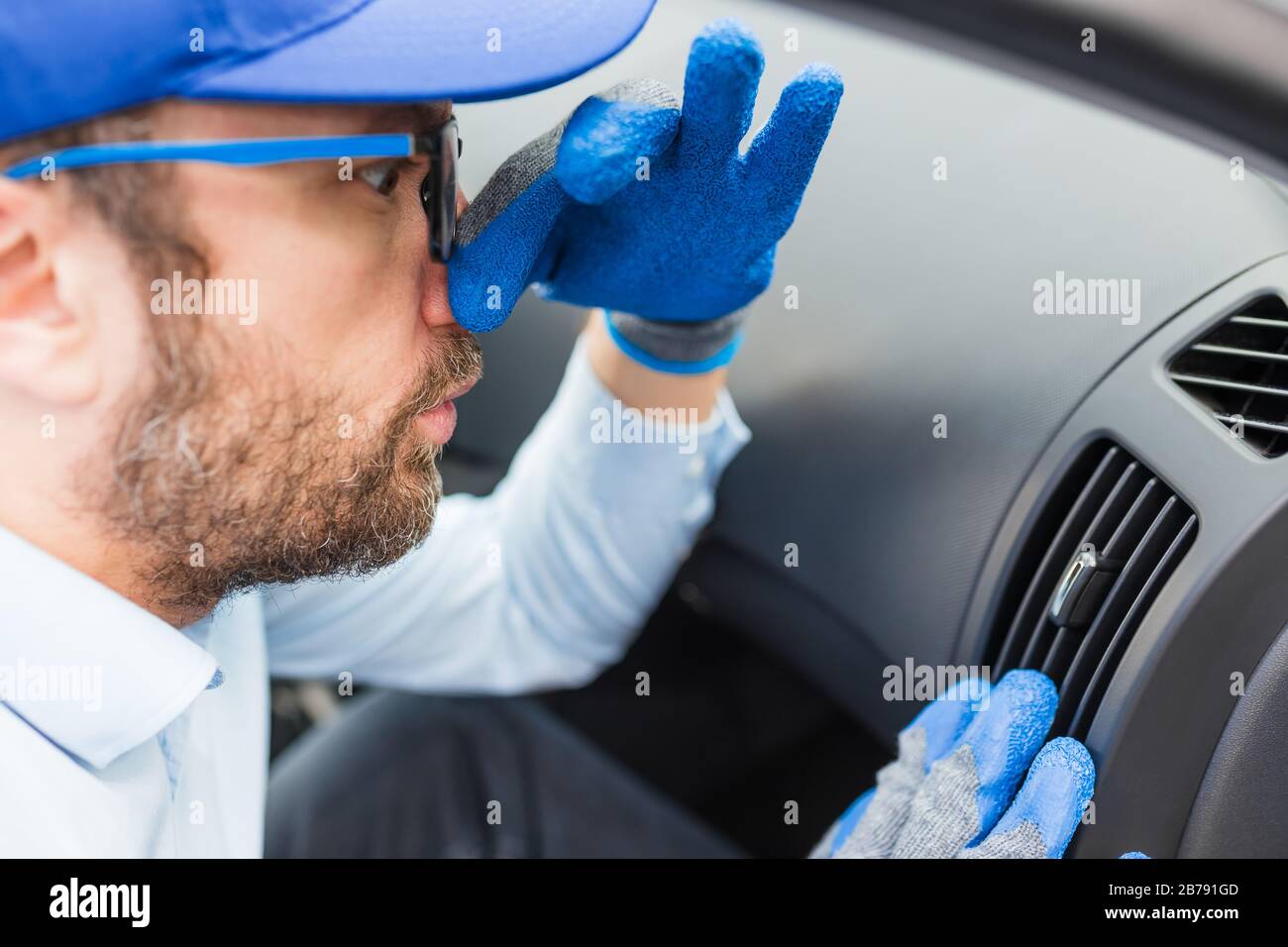 Car wash employee covering his nose with hand because of stink from air