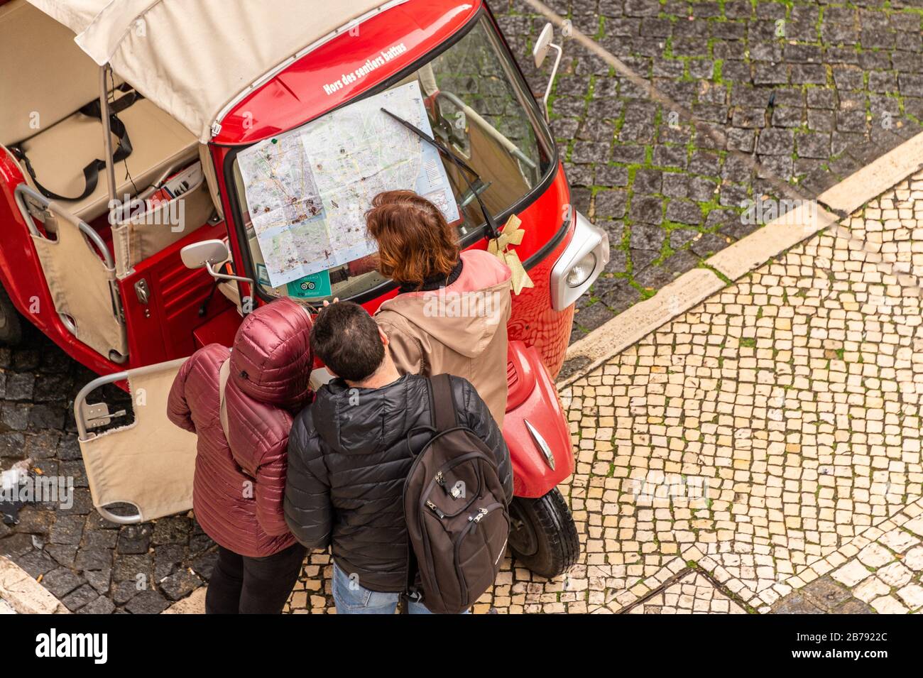 Lisbon, Portugal - 3 March 2020: Tour guide and tourists looking at Lisbon Map on Tuk Tuk windshield Stock Photo