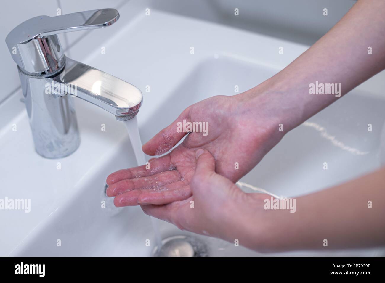 Woman thoroughly washing her hands with soap in the sink. Royalty free ...