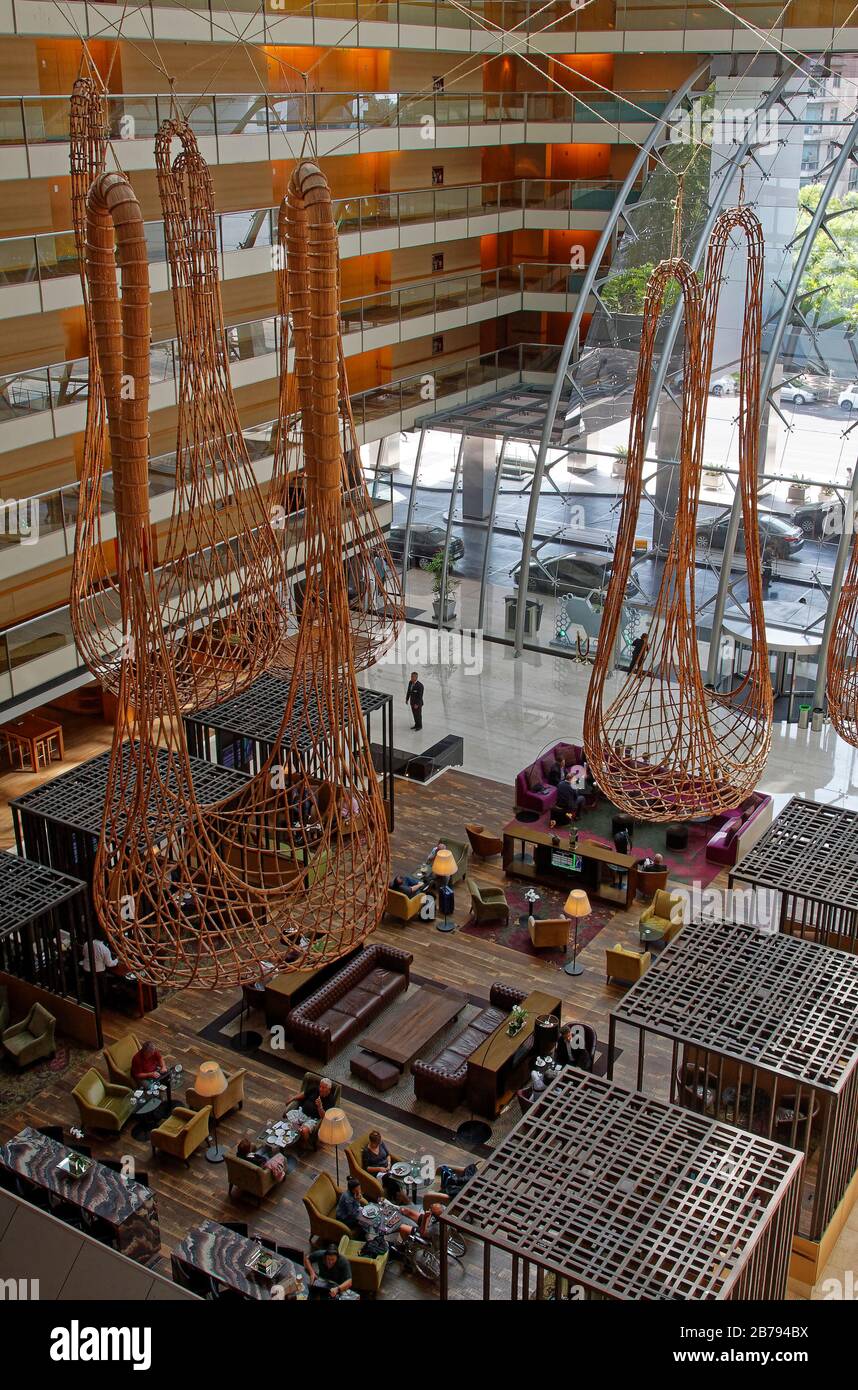 Hilton Hotel atrium; large decorations suspended, sofas, chairs, tables, people, balconies overlooking open space, South America; Buenos Aires; Argent Stock Photo