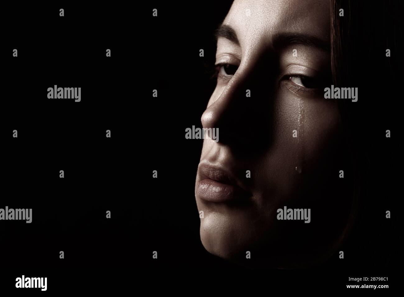 sad woman crying on black background with copy space, closeup portrait Stock Photo
