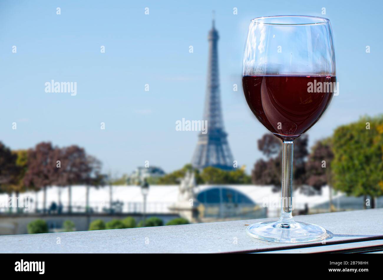 Glass of wine on Eiffel tower blur background. Sunny view of glass of