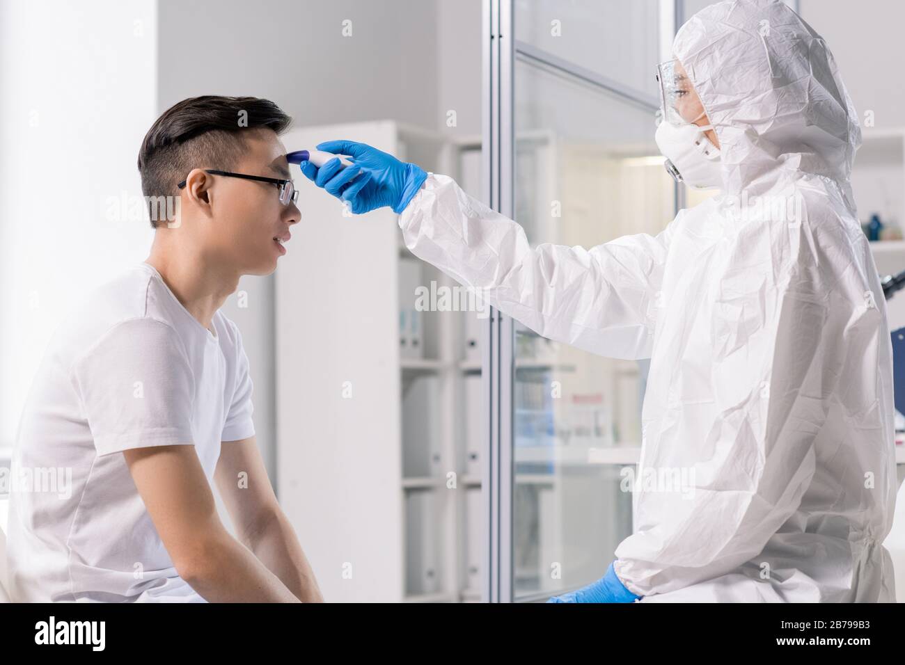 Laboratory worker in protective coveralls, mask, gloves and eyeglasses ...