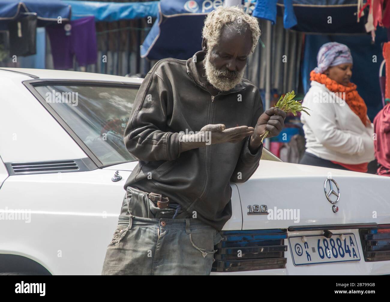 Senior ethiopian man leaning on a Mercedes car while chewing his khat leaves, Addis Ababa Region, Addis Ababa, Ethiopia Stock Photo