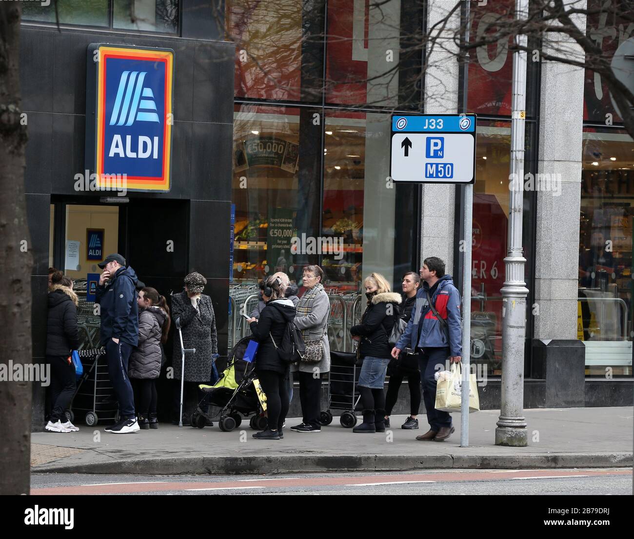 14/03/2020. Covid-19 Pandemic (Coronavirus) Ireland. A queue of people stand outside Aldi supermarket in Dublin as panic buying sets in. As of last night there were 90 cases of Covid-19, and one death confirmed in the Republic of Ireland. All major outdoor sporting events involving more than 500 people and indoor events of any kind with more than 100 people have been cancelled. All schools universities, childcare facilities, museums and art galleries have been closed. Most churches have cancelled services.  Photo: Sam Boal/Rollingnews.ie Stock Photo