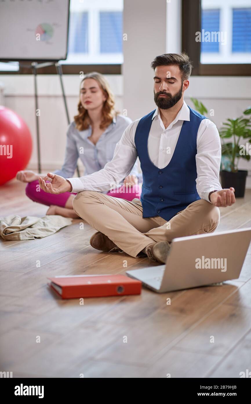 Modern man meditating at work.coworkers meditating together at work. Stock Photo