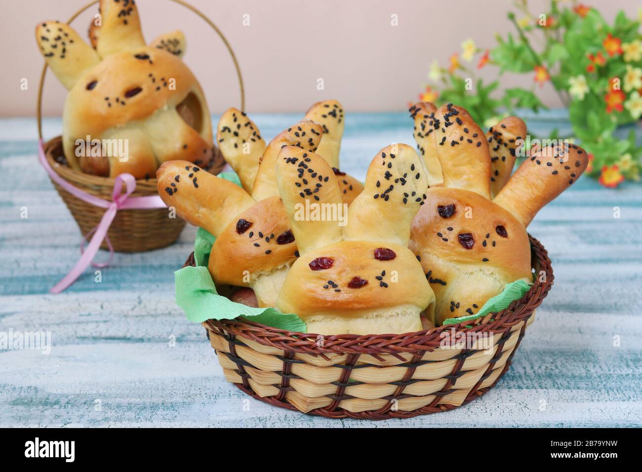 Easter Buns in the form of hares are located in a wicker baskets on a blue background, culinary idea for children Stock Photo