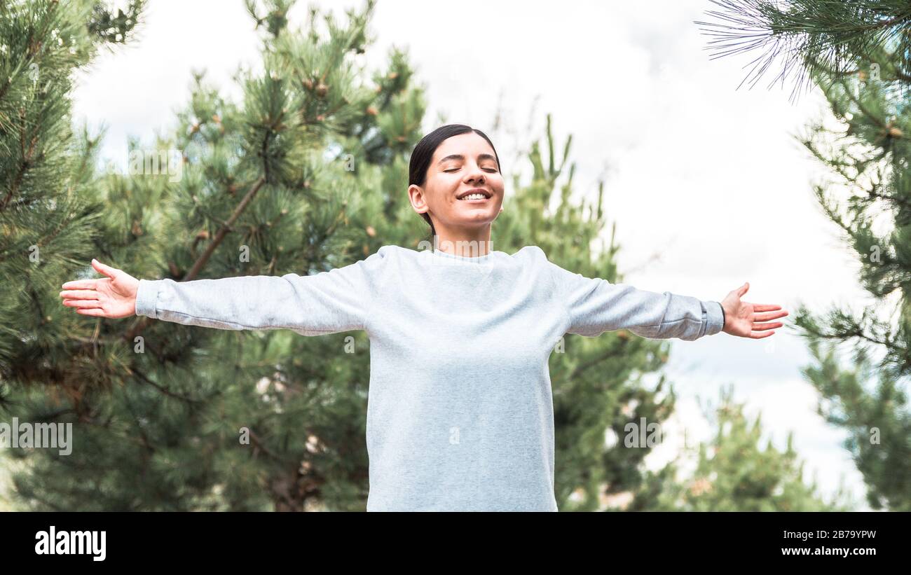soul and body freedom. attractive woman with arms open and eyes closed meditating and understanding her being in nature Stock Photo