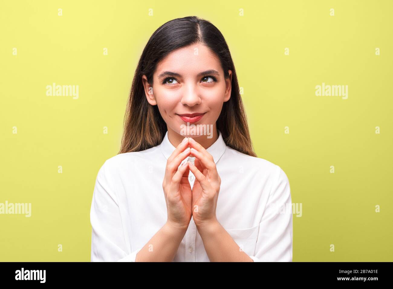 young sneaky woman, scheming something for april first, fools day against yellow background Stock Photo